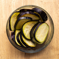 Fresh Sliced Eggplant in Glass Bowl on Wooden and Dark Background