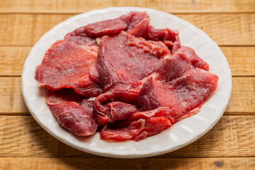 Fresh Raw Beef Slices on White Plate over Wooden Table