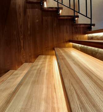 This modern illuminated wooden staircase combines the texture of natural wood with elegant black railings. Perfect for home and real estate design, it provides inspiration for sophisticated decor.