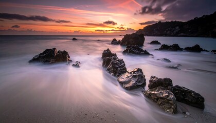 Beautiful coastal scene at sunset featuring smooth water, rocky formations, and a vibrant sky with colorful clouds