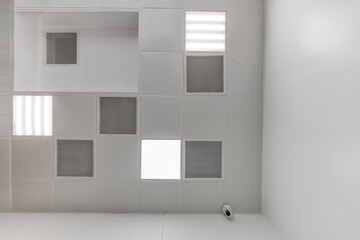 view straight up at cassette suspended ceiling with square fluorescent lights or halogen spots lamps  in a work area or hallway with ventilation