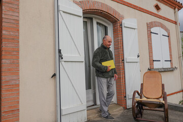 Fototapeta premium Man walks out of house holding folder in hand and smiles