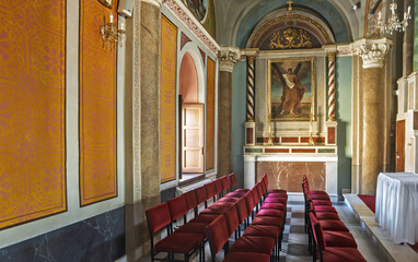  the Cathedral of Saint George in Ano Syros showcasing  columns, arches, and a vaulted ceiling with intricate artwork. The central altar is draped in white cloth and framed by golden columns 