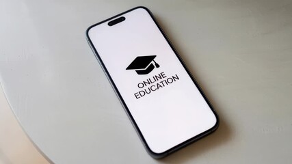 Smartphone displays an online education logo on a minimal light table surface. Clean composition emphasizes digital learning and remote study access. Neutral tones and soft shadows convey a profession - Powered by Adobe
