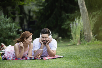 Couple listening to music while laying on blanket in park