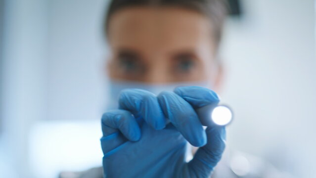 Therapist checking light reaction in clinic ward. Doctor with flashlight closeup