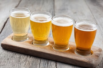 Craft beer flight presents four diverse samples on wooden tasting paddle, showcasing different styles