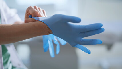 Doctor hands putting gloves preparing to medical procedures at cabinet closeup