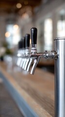 Multiple shining chrome beer taps lined up on modern wooden bar counter, illuminated by soft bokeh lights