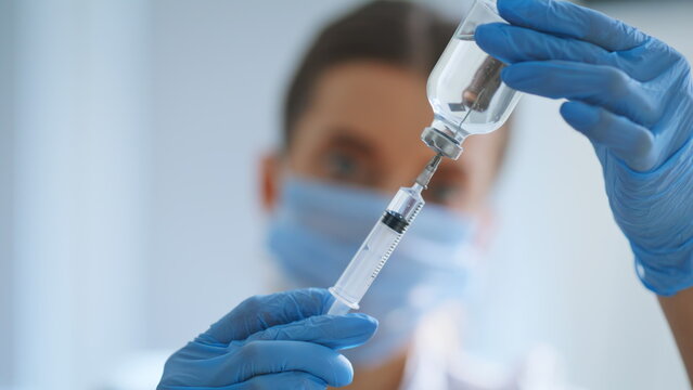 Medical syringe fulled drug in doctor hands closeup. Nurse holding injection