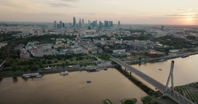 Establishing aerial view of Warsaw skyline above Swietokrzyski Bridge at golden hour. Cinematic riverfront cityscape of Poland Capital with iconic landmarks. 4K drone orbitshot