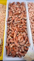 Frozen shrimp displayed at a fishmonger's stall, photographed in a market setting. High-quality seafood retail image showcasing texture, frost, and freshness