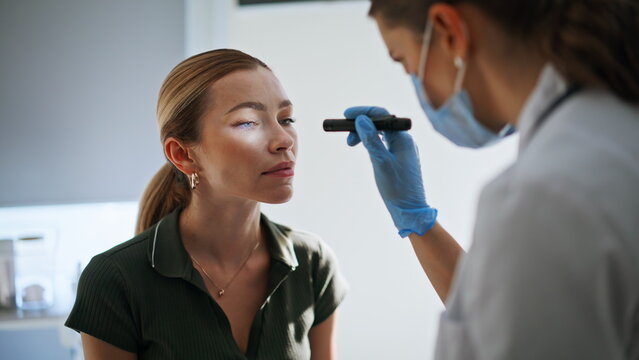 Neurologist testing woman eyes reflexes during checkup. Doctor checking health