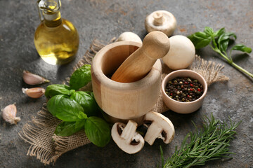Wooden mortar with peppercorns, different herbs and fresh mushrooms on dark background