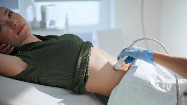 Closeup doctor examining ultrasound pregnancy clinic. Hand using medical machine - Powered by Adobe