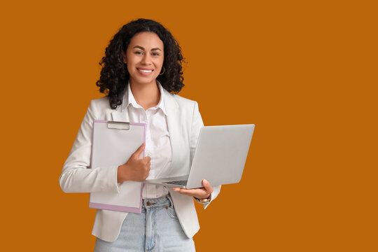Female African-American job applicant with laptop and clipboard on orange background