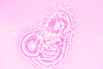 Pink water bubbles on the surface ripples. Defocus blurred transparent pink colored clear calm water surface texture with splash and bubbles. Water waves with shining pattern texture background