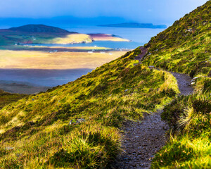 Vertical view of Quiraing trail on Isle of Skye overlooking the sea, green Scottish highlands with winding path and open landscape, peaceful hiking and travel background.