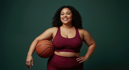 Confident plus-size woman in sportswear holding basketball. Happy female athlete smiling in studio. Body positivity and active lifestyle concept with copy space