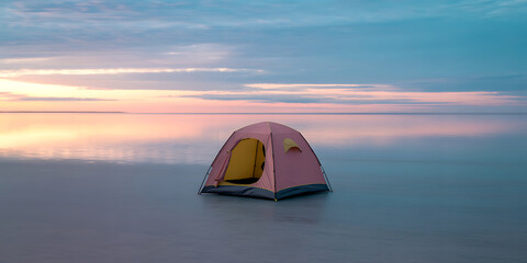 Serene pink tent on calm water at sunset with vibrant sky