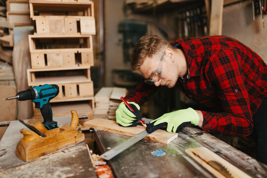 Young stylish carpenter wearing a shirt working in his workshop, focusing on a woodworking project