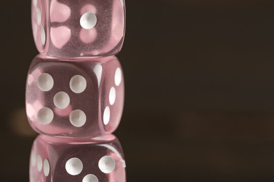 Pink game dices on wooden background, closeup