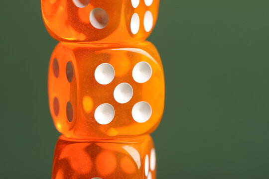 Orange game dices on green background, closeup