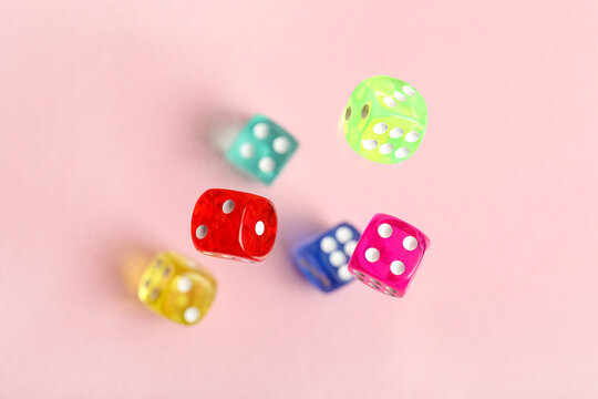 Flying colorful game dices on pink background
