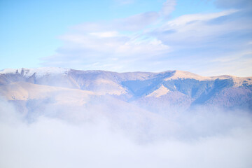 Serene mountain landscape with misty clouds and snow-capped peaks in bright blue sky