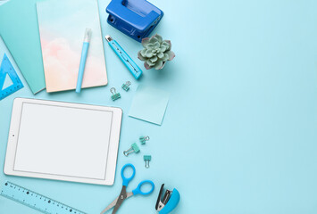 Fototapeta premium Set of school stationery with tablet computer and houseplant on blue background