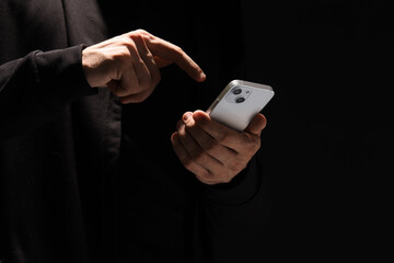 Male fraudster using mobile phone on black background, closeup