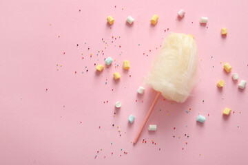 Composition with stick of tasty cotton candy and marshmallows on pink background