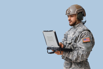 Male soldier working with military laptop on light background