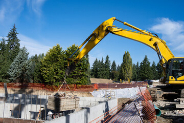 Heavy equipment operator using strap on excavator boom arm to remove stack wood concrete pouring...