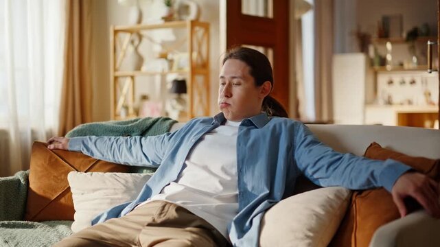 Asian man taking sit falling sofa at home closeup. Exhausted guy having rest