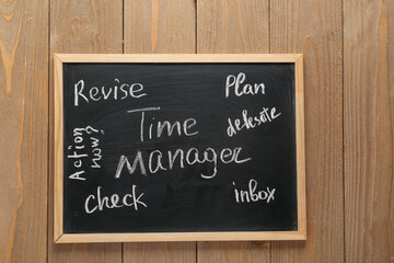 Fototapeta premium Blackboard with text TIME MANAGER on wooden background. Top view