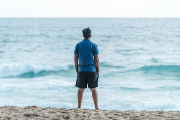 Man contemplating ocean vista from sandy beach
