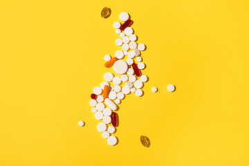 Composition with different pills on yellow background