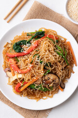 Japchae, Korean stir fried glass noodles with vegetables, pork, soy sauce and sesame seeds, Top view