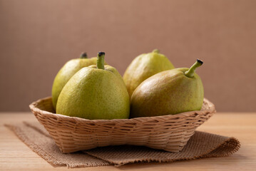 Fresh pear in basket on wooden background