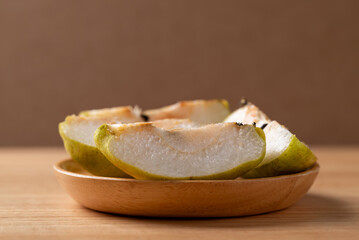 Sliced pear in wooden plate on wooden background
