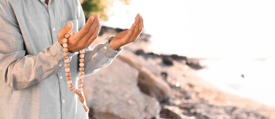 Young Muslim man praying outdoors, closeup
