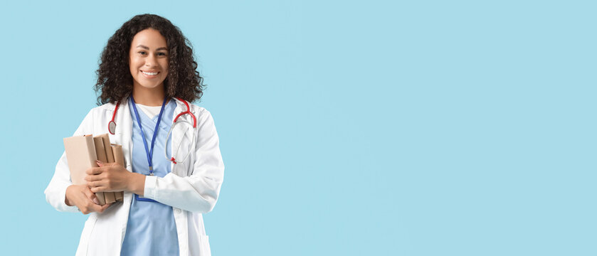 Female African-American medical student with books on blue background