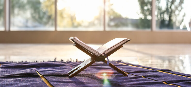 Rehal with open Koran on Muslim prayer mat indoors