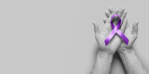Hands holding purple awareness ribbon on grey background with space for text. World Cancer Day