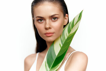 Young model with green leaf, promoting natural beauty and wellness in a bright, minimalistic setting, ideal for eco-friendly concepts.