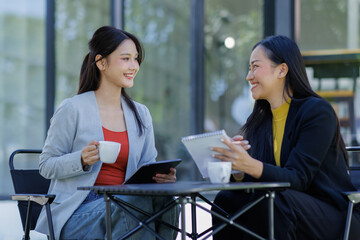 Obraz premium Two business working together using digital tablet pc and talking about a business project. Small creative diversity team of females executives meeting work in office. 