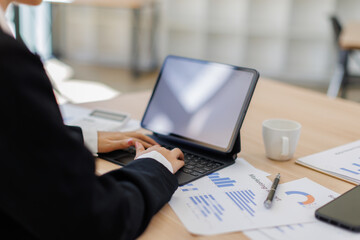 Asian Business woman using calculator and tablet laptop for doing math finance on an office desk, tax, report, accounting, statistics, and analytical research concept

