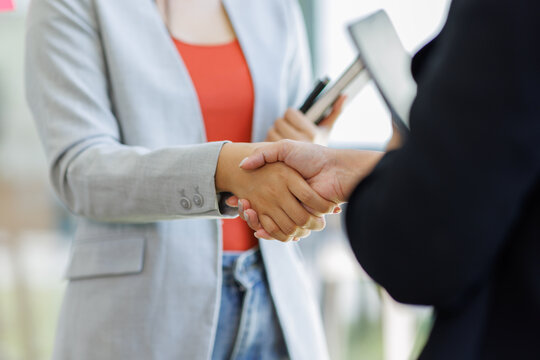Happy business asian manager handshaking client at meeting. Smiling female hr hiring recruit at job interview, insurance agent, lawyer making contract deal at work with business handshake.

