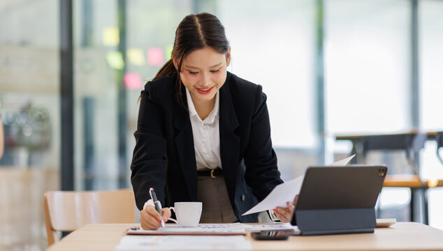 Asian Business woman using calculator and laptop for doing math finance on an office desk, tax, report, accounting, statistics, and analytical research concept
- Powered by Adobe